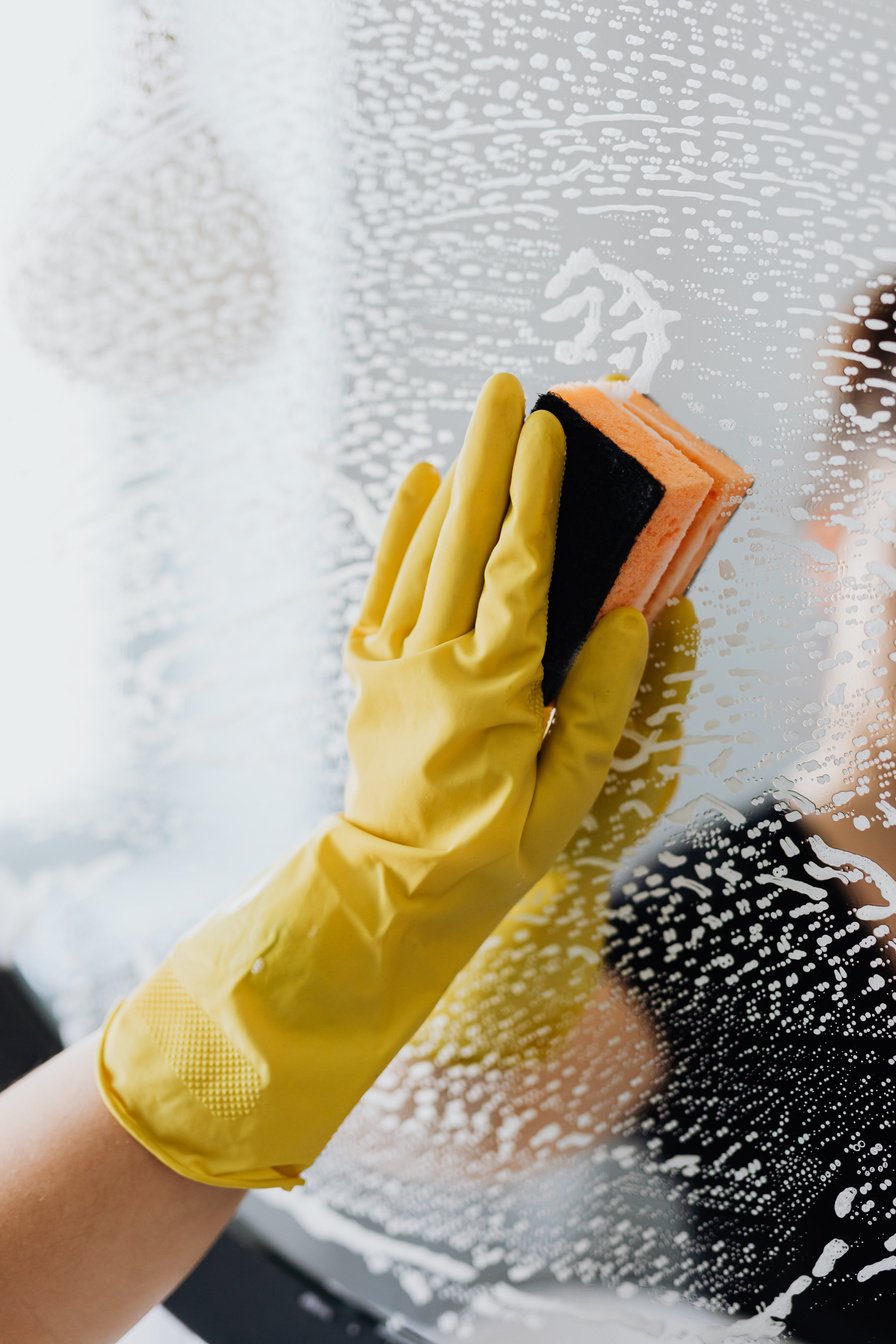 Anonymous person cleaning mirror with sponge